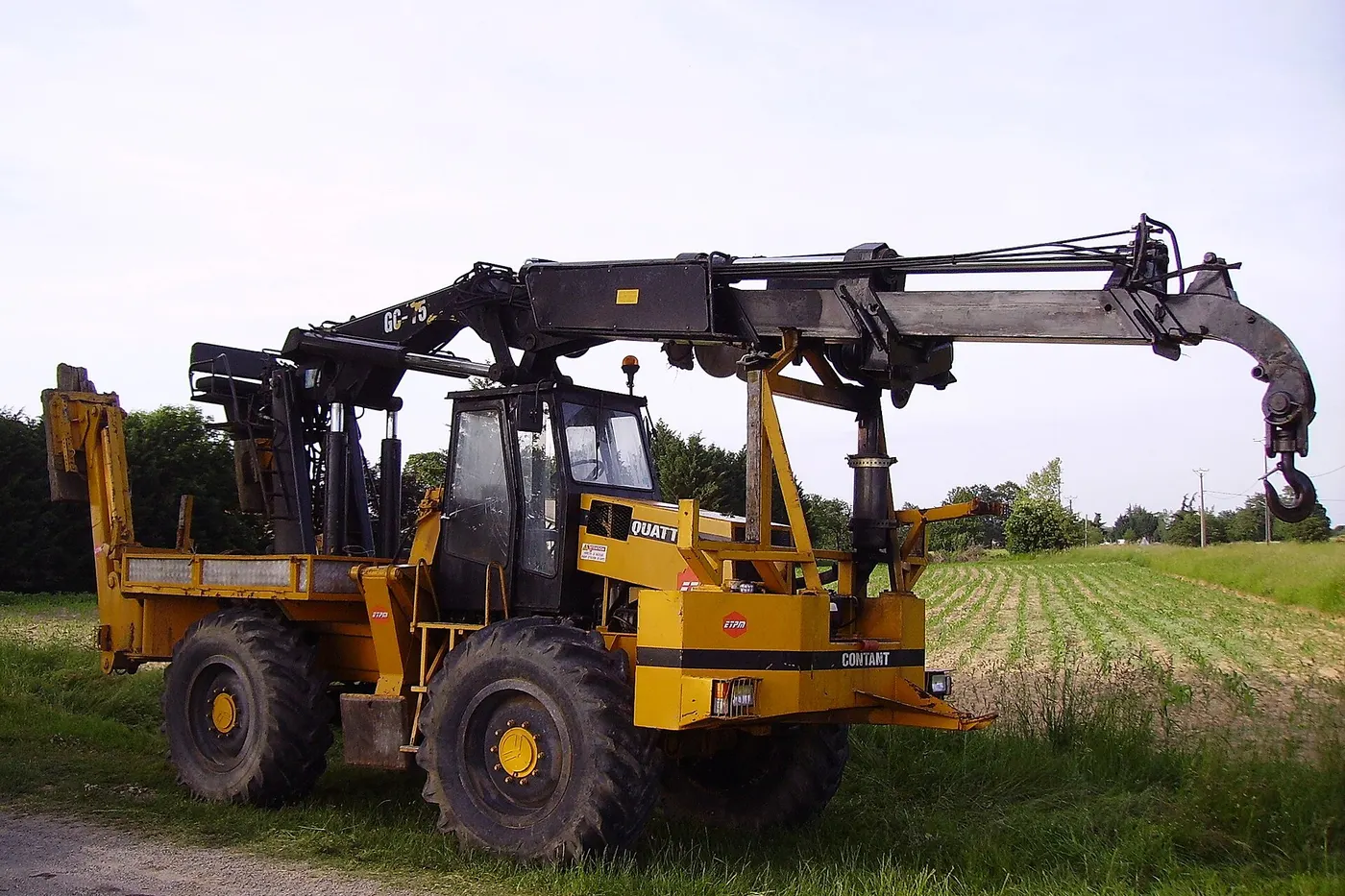 Rough-terrain crane parked beside a green field